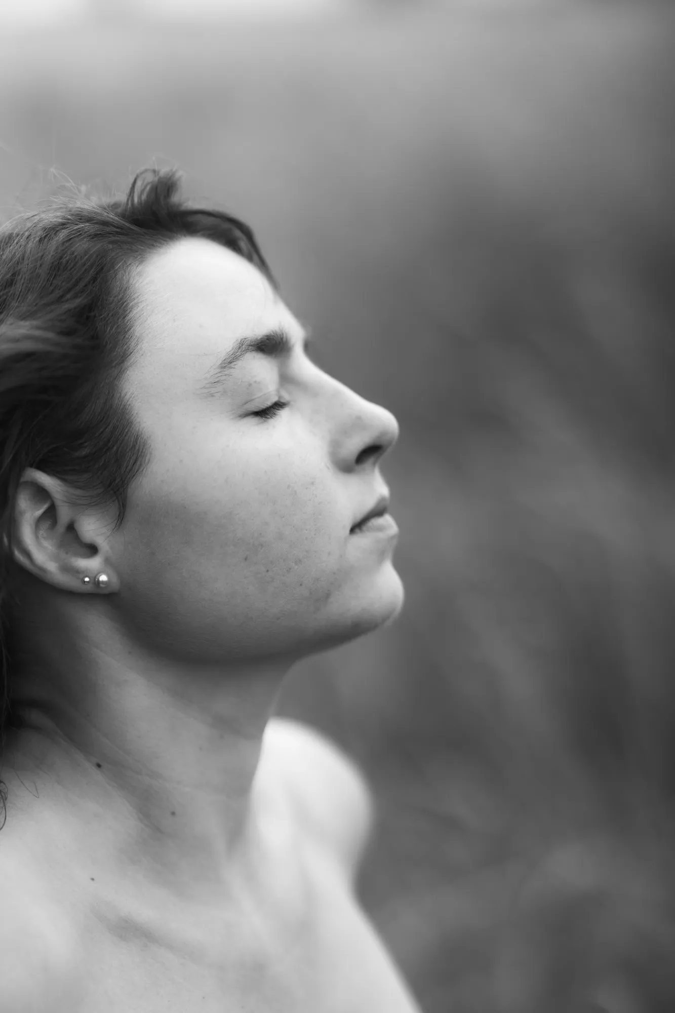 Profil einer Frau mit geschlossenen Augen, das Gesicht dem Himmel zugewandt