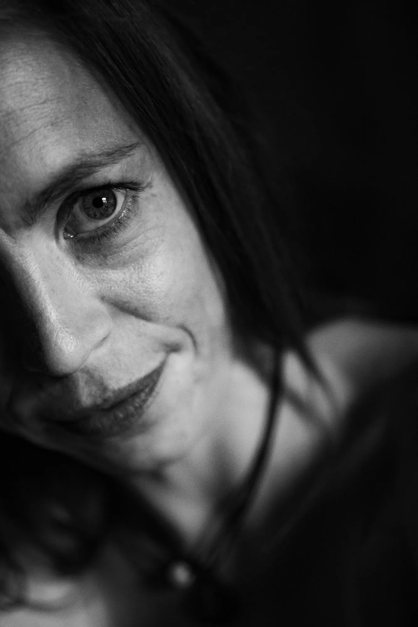 Schwarzweiß: Nahaufnahme eines Gesichts im Halbschatten, ein Auge blickt direkt in die Kamera